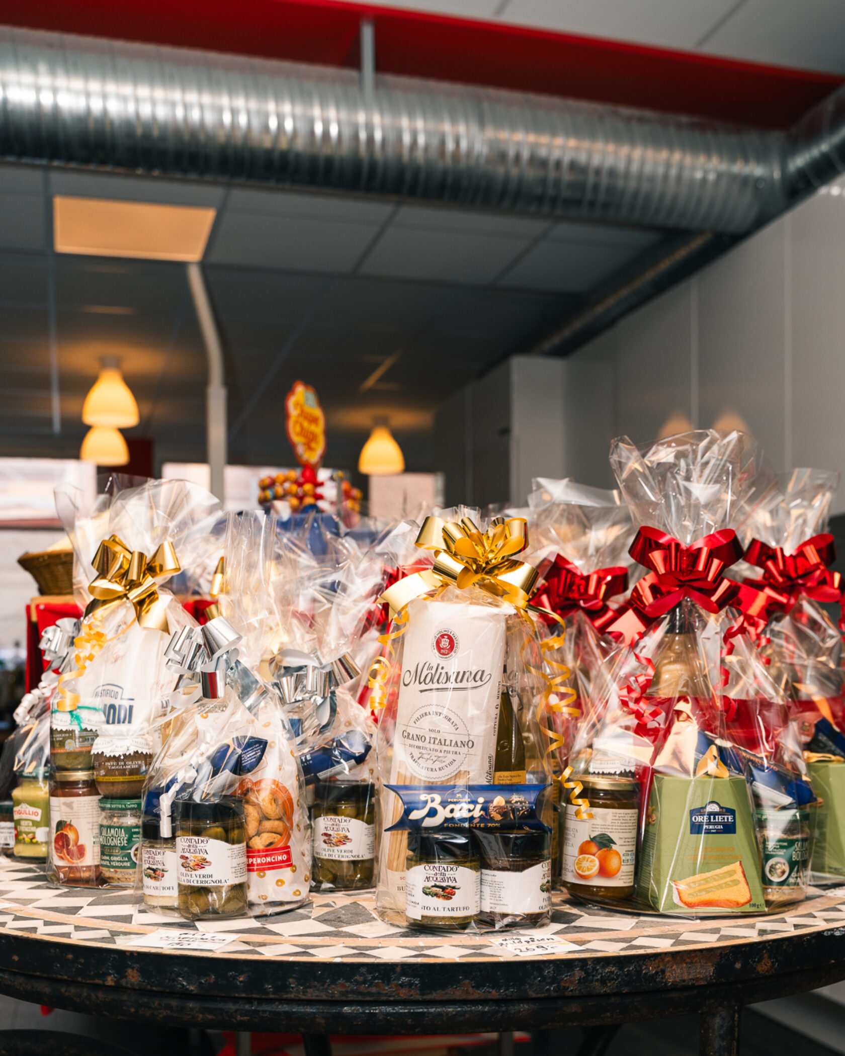 Julpåsar med italienska delikatesser, inslagna och dekorerade med röda, guld- och silverfärgade rosetter, står uppställda på ett bord